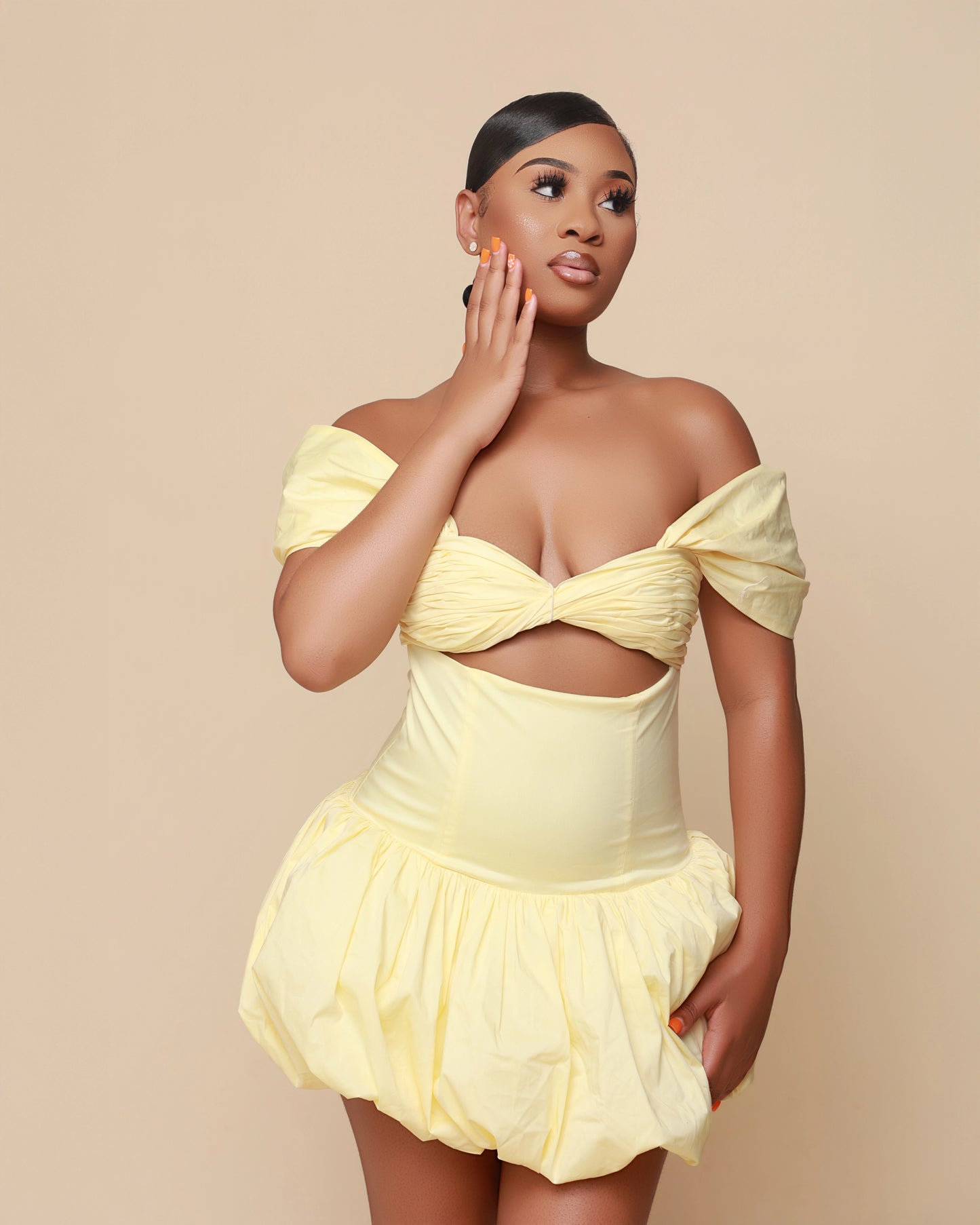 Woman wearing a yellow off-shoulder dress on a beige background